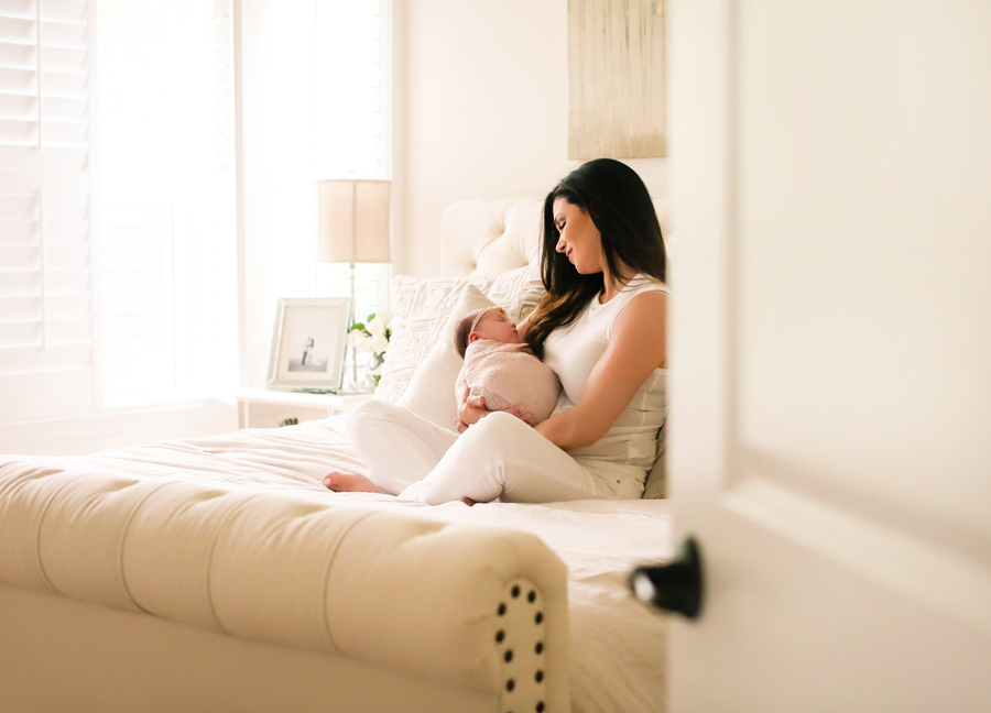 Image of a mother holding her swaddled baby at an in-home newborn session in Chandler, Arizona