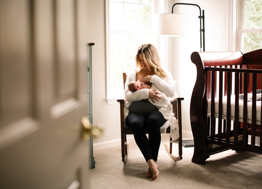Image of a mother nursing her baby in a rocking chair at an in-home newborn session in Chandler, Arizona