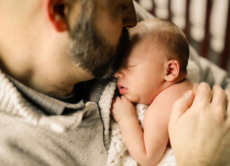 A father kissing his newborn baby at an in-home newborn session in Chandler, Arizona