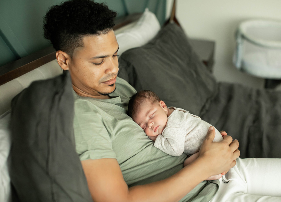 A father holding his newborn baby during a In Home Newborn Photography Session