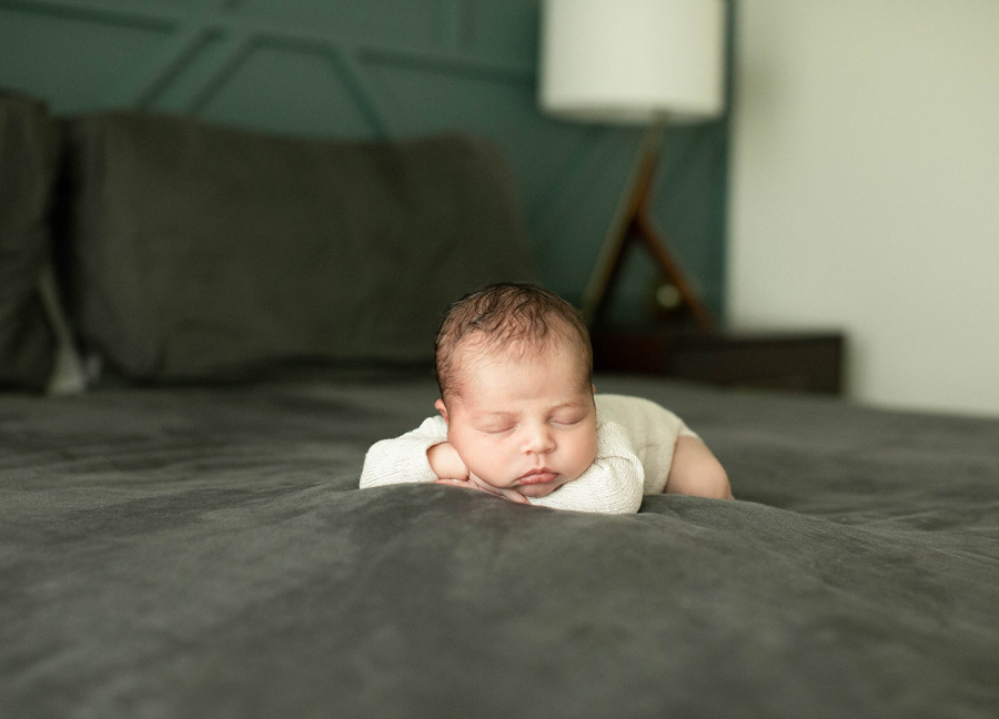 A baby boy posed on the master bed during a newborn photo shoot with Northern Virginia newborn photographer, Stephanie Honikel Photography.