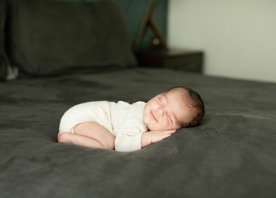 A smiling baby sleeping on his tummy during a Northern Virginia newborn photography session with Stephanie Honikel Photography.