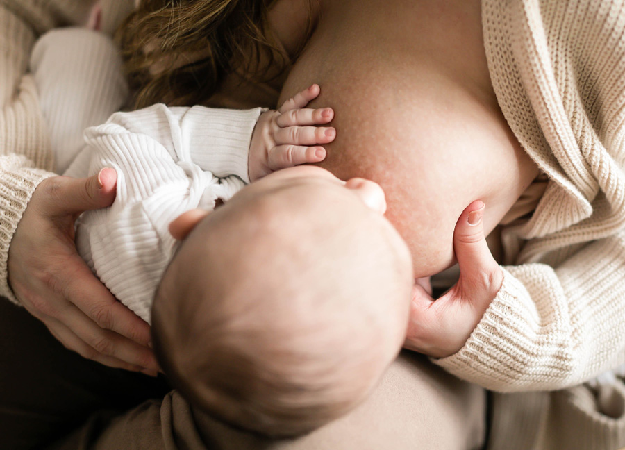 A mom breastfeeding her baby at a Northern Virginia newborn photography session with Stephanie Honikel Photography. 