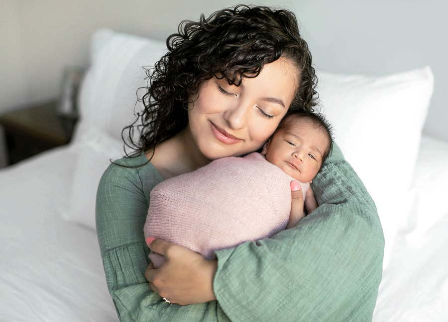 A mother holding her swaddled baby girl during their newborn photography session with D.C. newborn photographer, Stephanie Honikel Photography. This is one of the best newborn photo poses