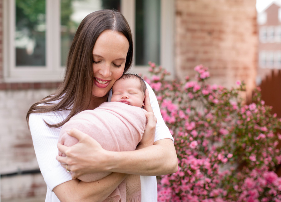 A mother holding her swaddled baby girl during an outdoor newborn photo session in Northern Virginia.