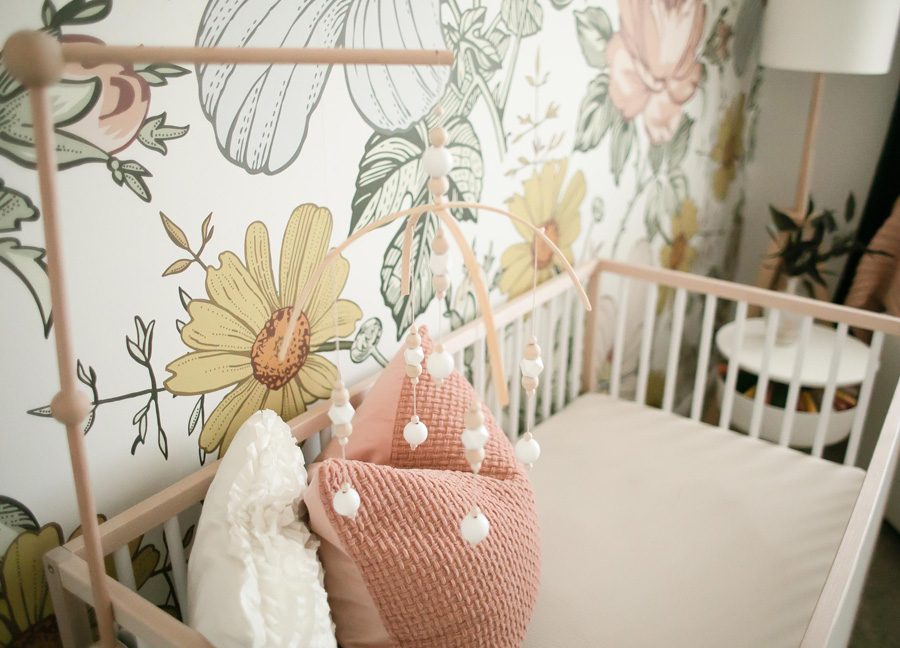 tips for decorating your nursery starts with a crib, which is shown in the picture along with flower wallpaper