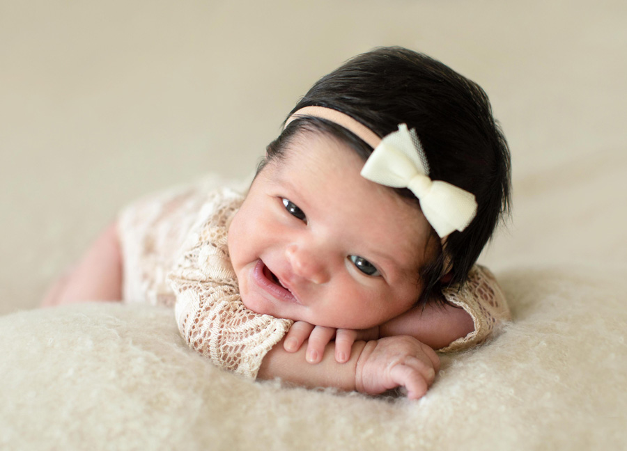 A smiling newborn baby with her eyes open captured by Washington, D.C. newborn photographer Stephanie Honikel.