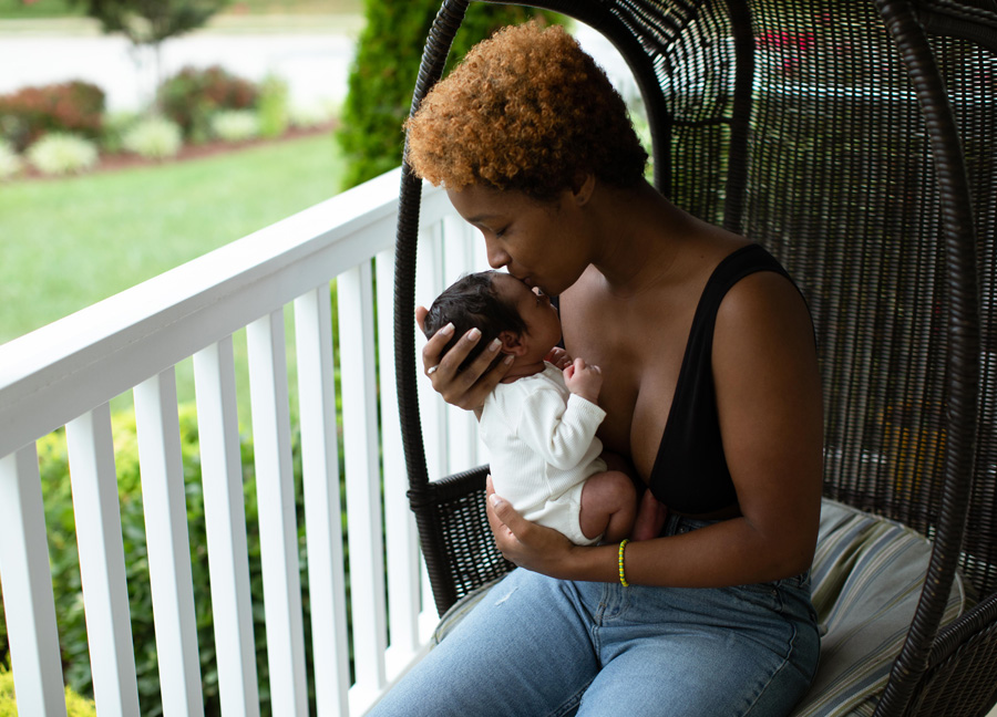 A mother kissing her newborn baby on the front porch of their home in Northern Virginia.