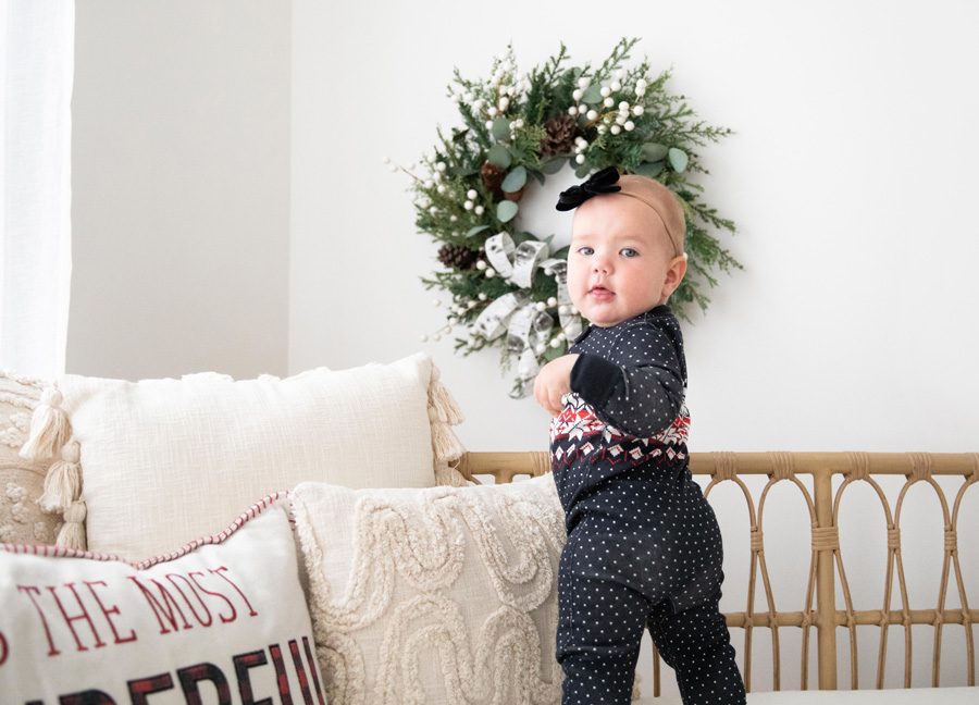 2022 Holiday Mini Sessions captures a little girl standing on the bed