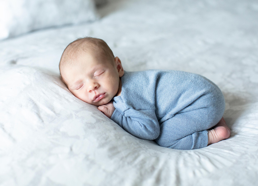 A sleeping baby boy in the tushy up pose on a master bed - Lifestyle versus posed newborn photography