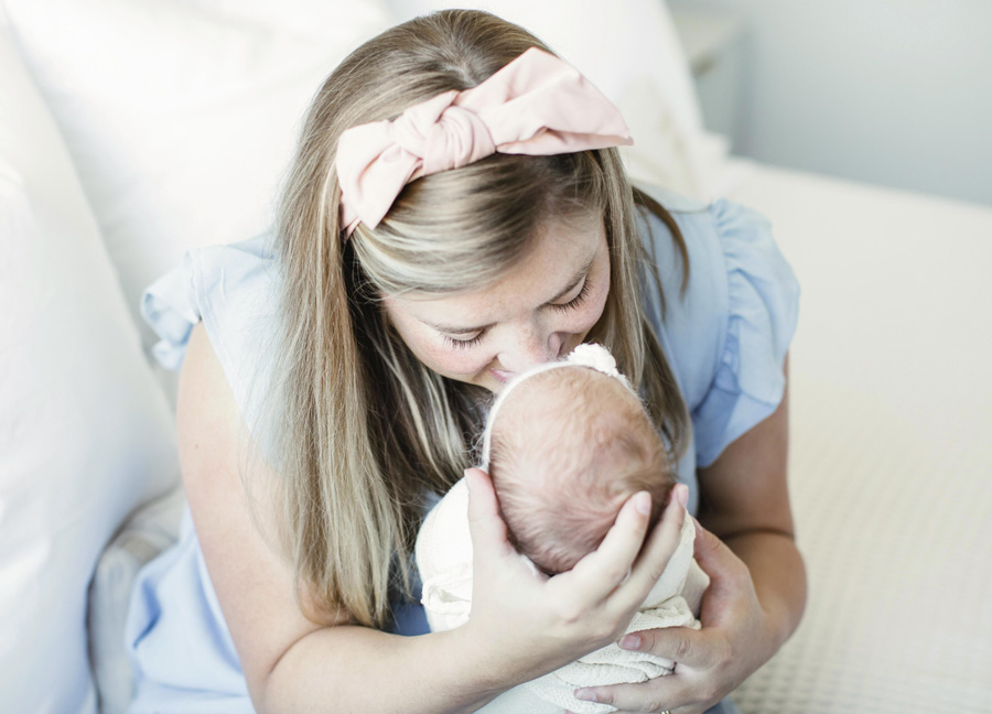 tips for the first week with a newborn series featuring a mom kissing her newborn