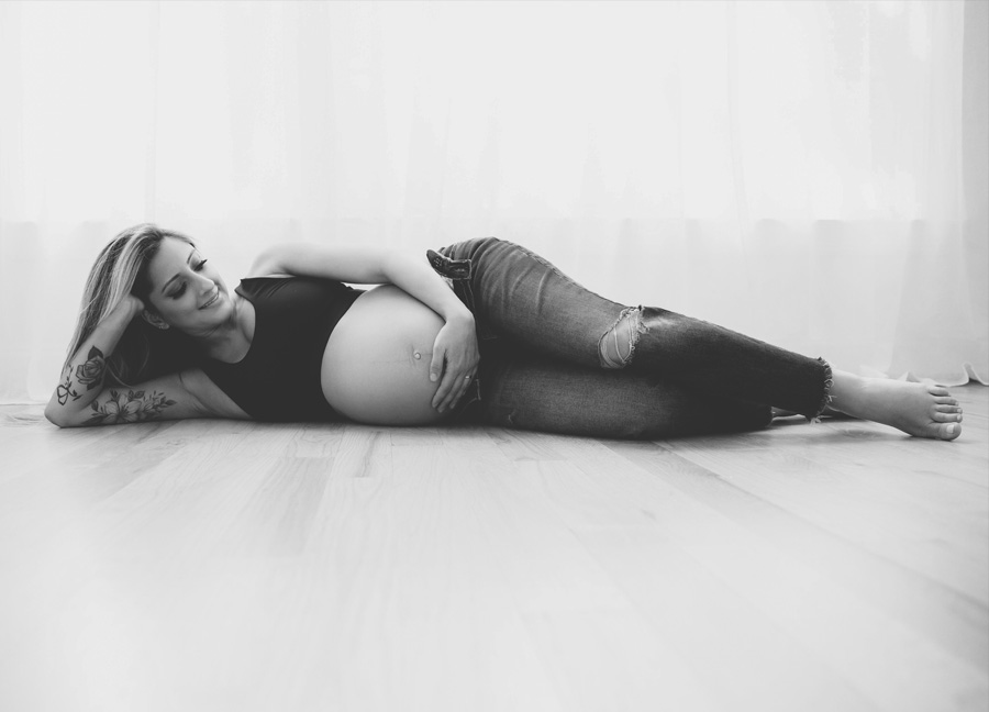 A pregnant woman in jeans and bra laying on the floor - c-section care tips
