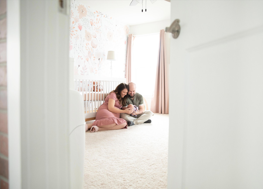 Parents in the nursery holding their baby girl during a newborn photo session in Leesburg, Virginia.
