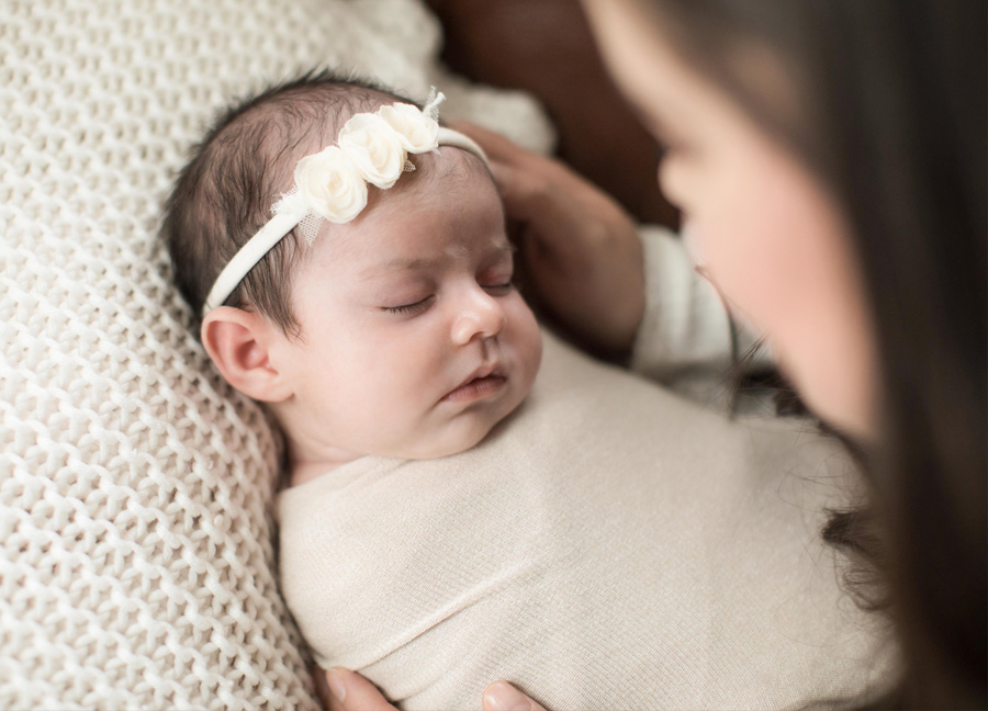A swaddled baby girl in the arms of her mother captured by Washington D.C. newborn photographer, Stephanie Honikel.