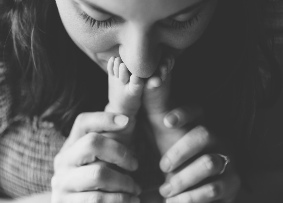 A mother kissing her baby's feet during an in-home newborn session in Northern Virginia. 