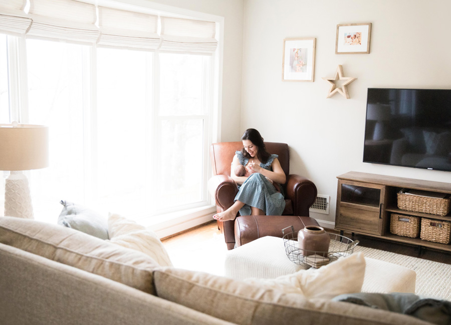 A mother nursing in her living room during an in-home newborn session in Northern Virginia. 