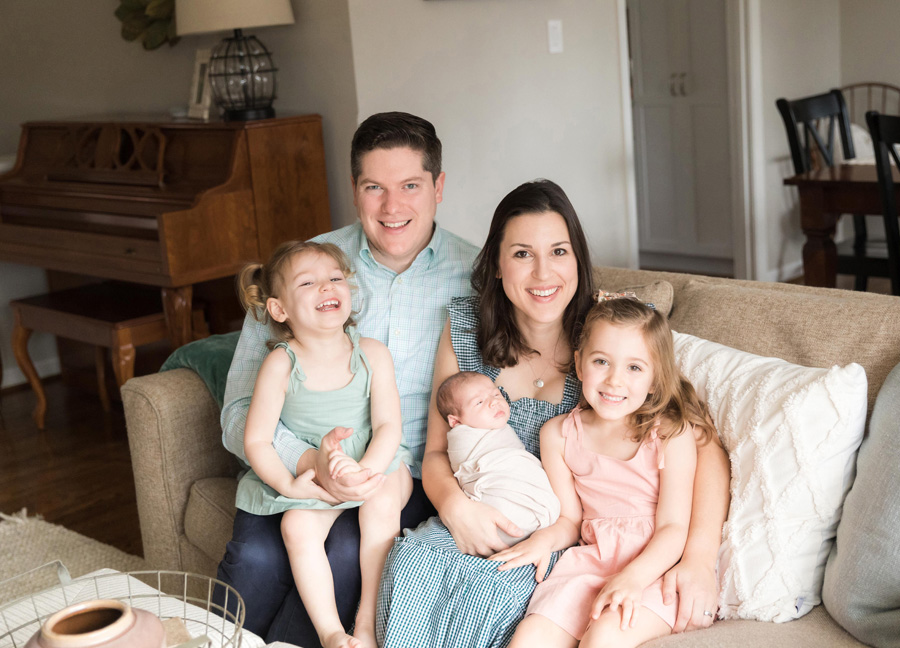 A family of five with a newborn and young siblings on a sofa during an in-home newborn session in Northern Virginia. 
