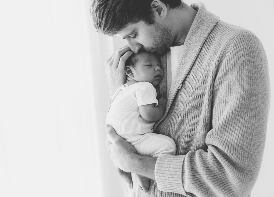 A father holding and kissing his baby boy during a newborn studio photography session with Stephanie Honikel. 