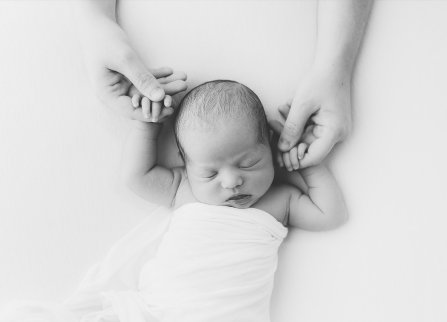 A mother holding her newborn's hands.