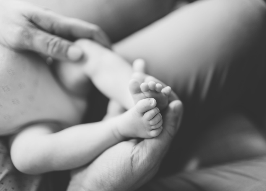 Baby feet in the hands of her father. 