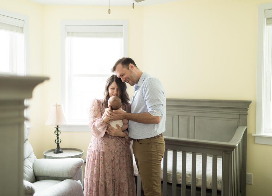 Mother and father holding their newborn baby in the nursery during their in-home newborn session in Washington, DC.