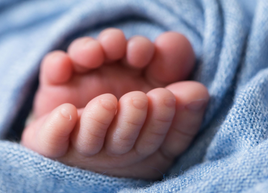 Image of baby toes wrapped in a blue swaddle. 