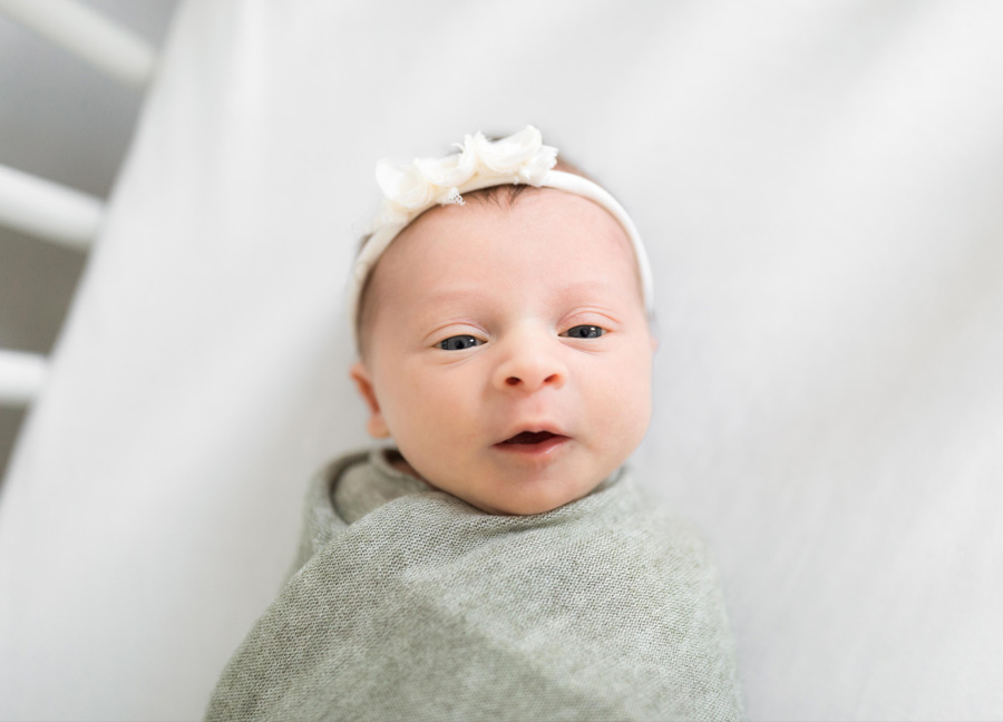 prepare for a new baby with a newborn phorgraphy shoot. This picture shows a baby girls face while she is laying in her crib
