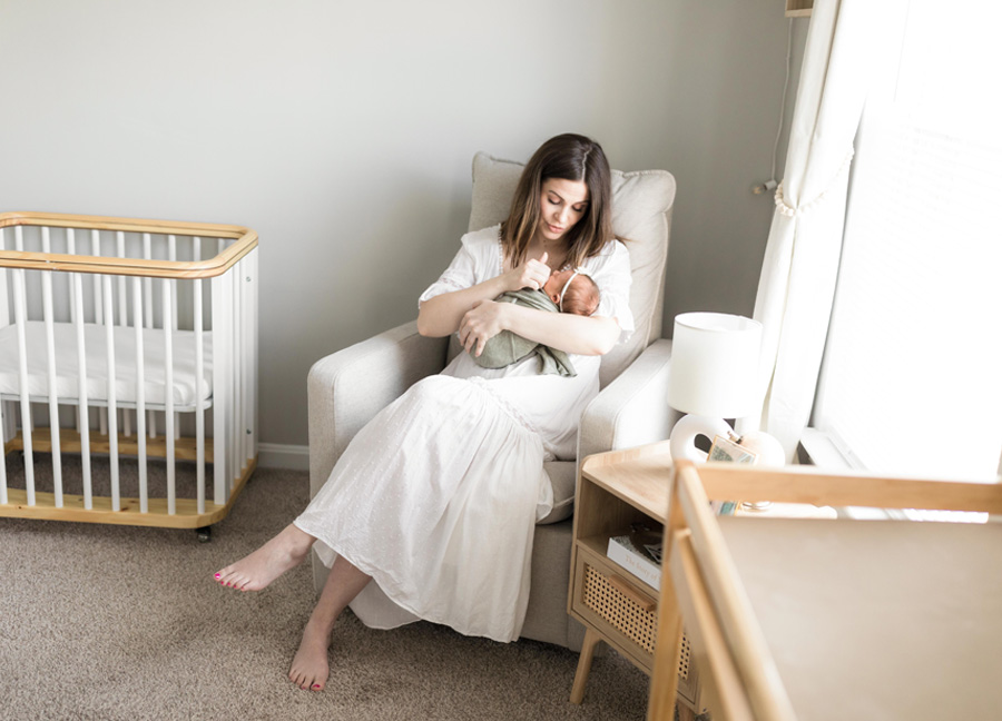 newborn photography in Washington D.C. with a Mom and baby sitting in a chair in a nursery. 