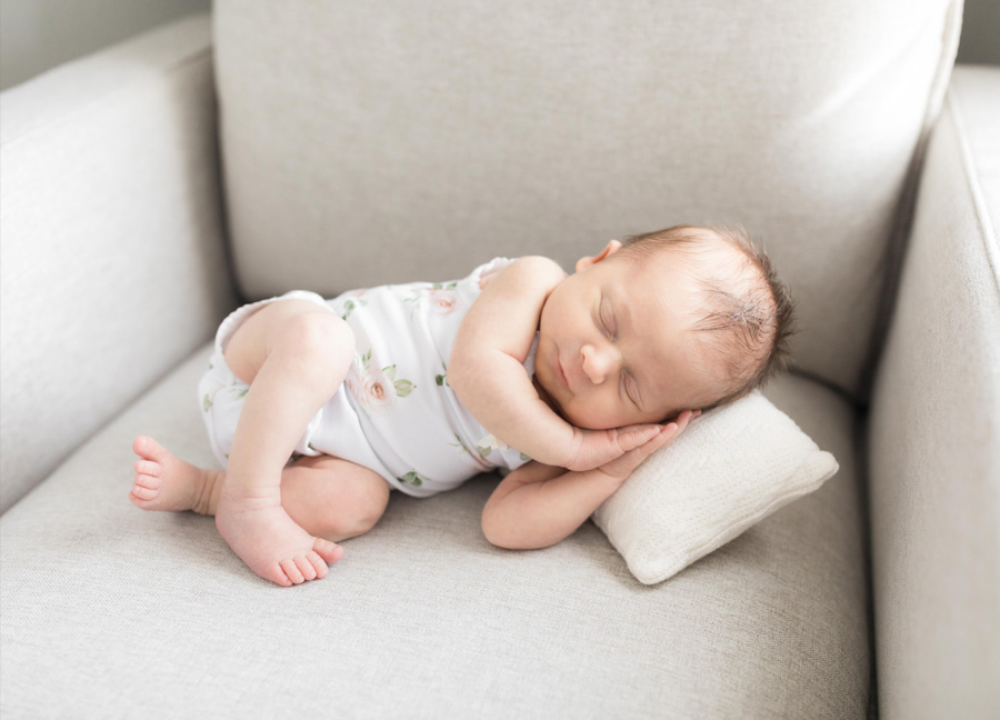 baby girl sleeping on a pillow on her nursery chair shot by a Washington D.C. newborn photographer