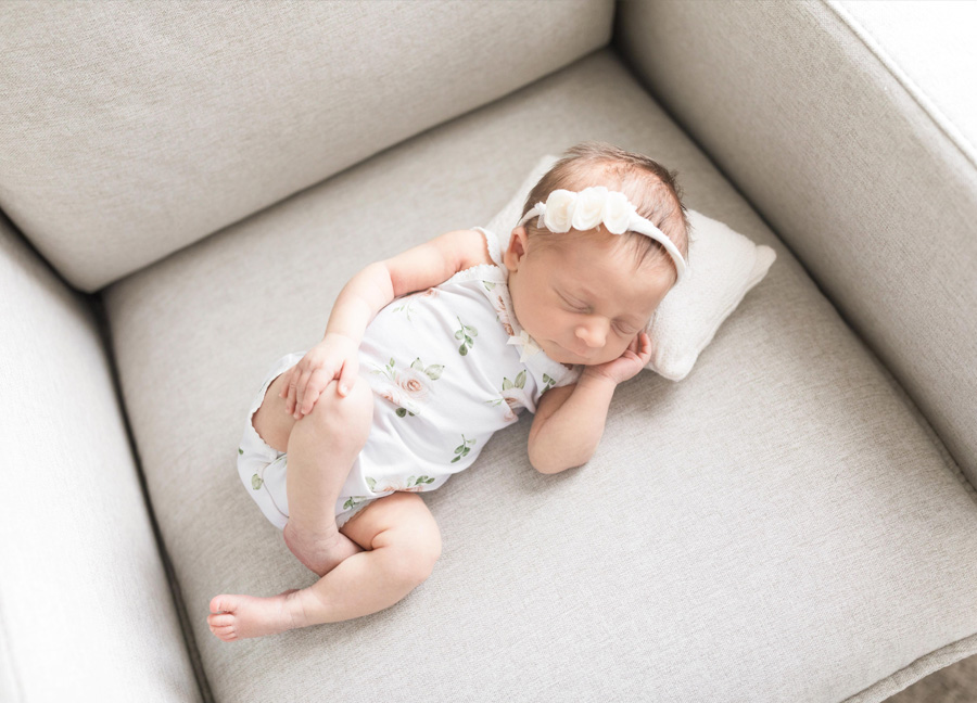 angle from above of a newborn sleeping on a pillow on her nursery chair shot by a newborn photographer in D.C.