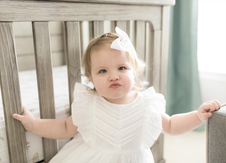 newborn photography in Northern Virginia featuring a toddler girl with a white dress and bow