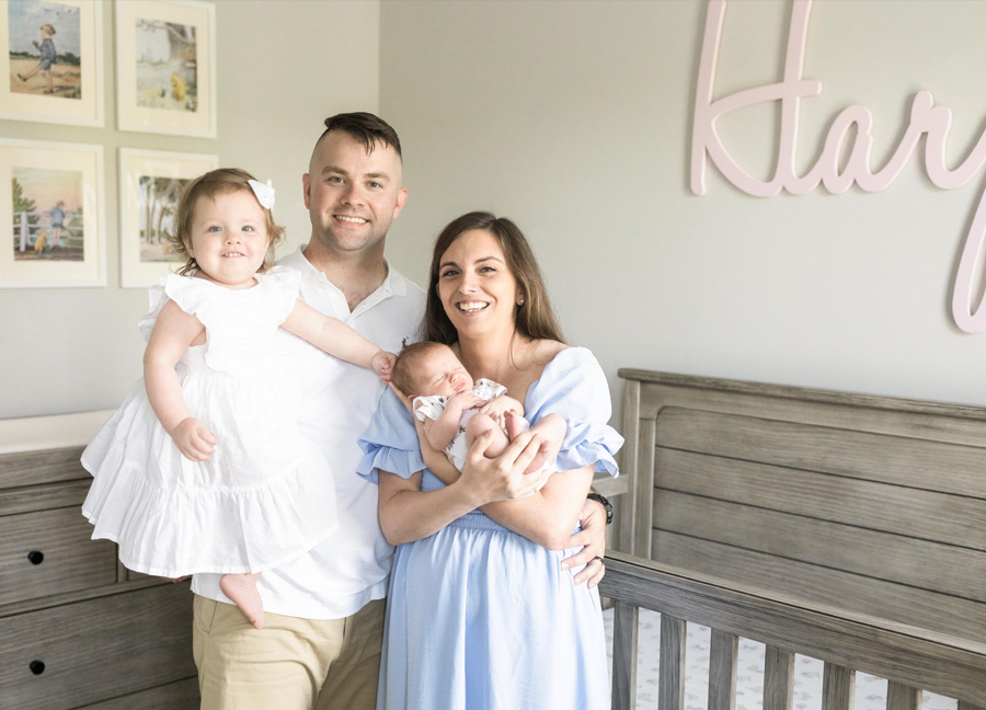 Family of four smiling in a nursery shot by newborn photographer in D.C.