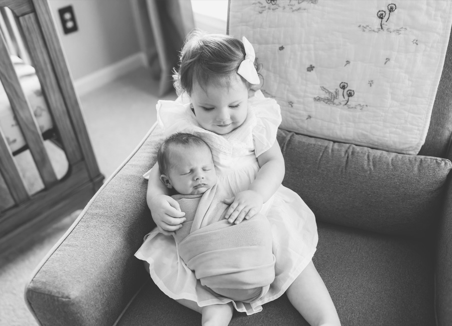 Black and white photo of toddler and newborn baby girl. 