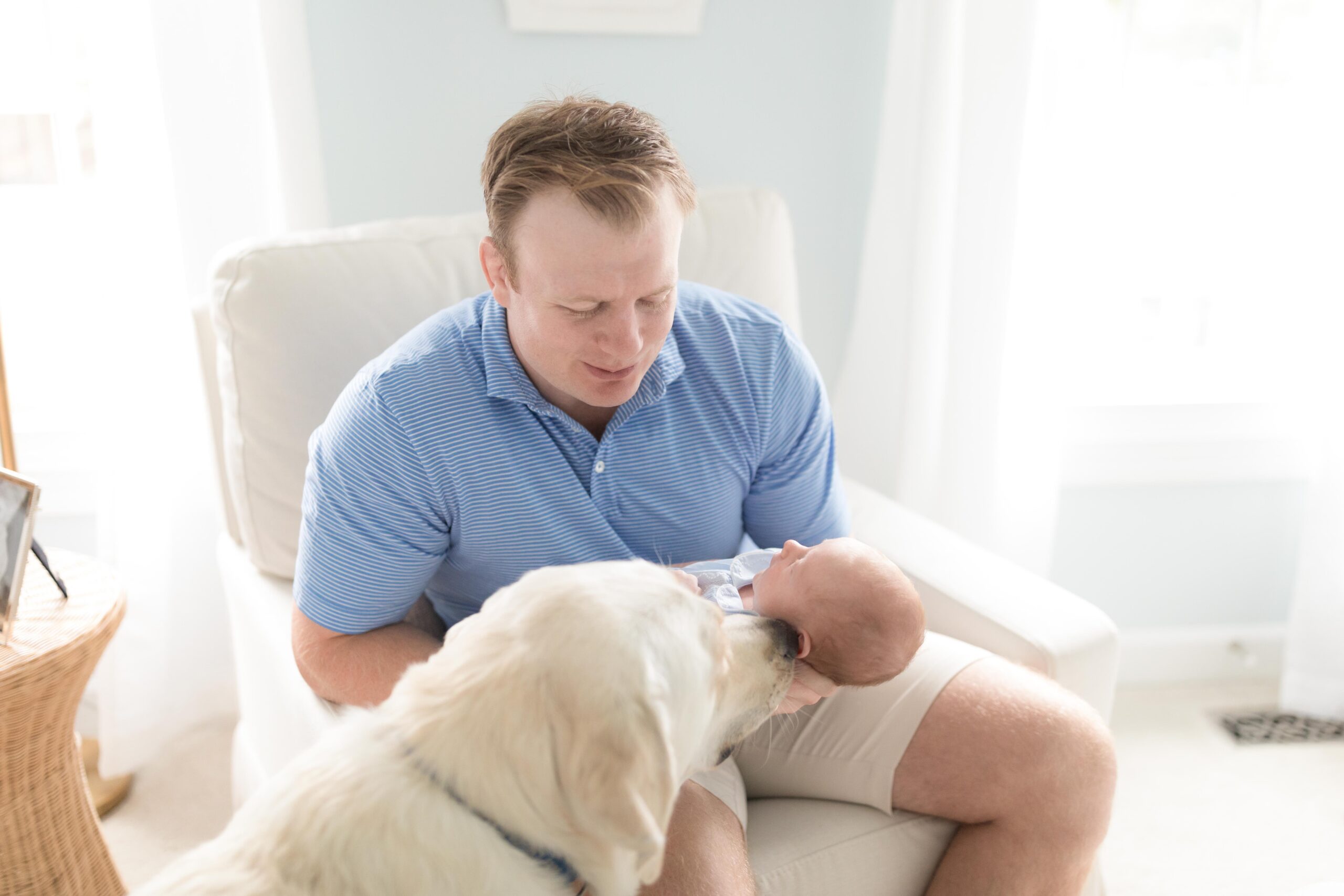 newborn photographer in D.C. captures a new father holding a baby with the family dog sitting beside them.