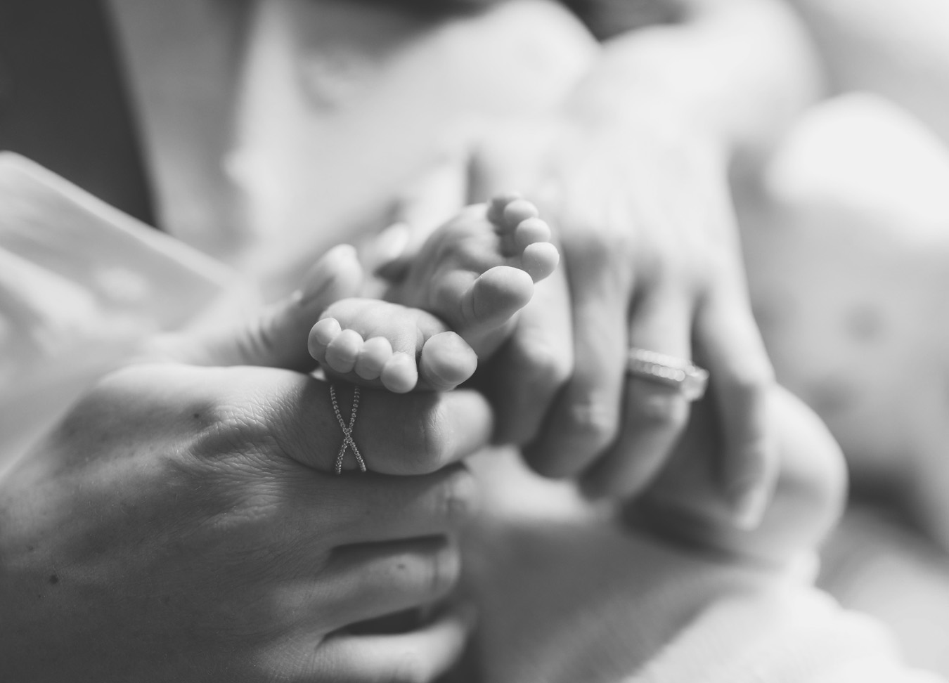 black and white image of tiny baby feet in her mother's hands