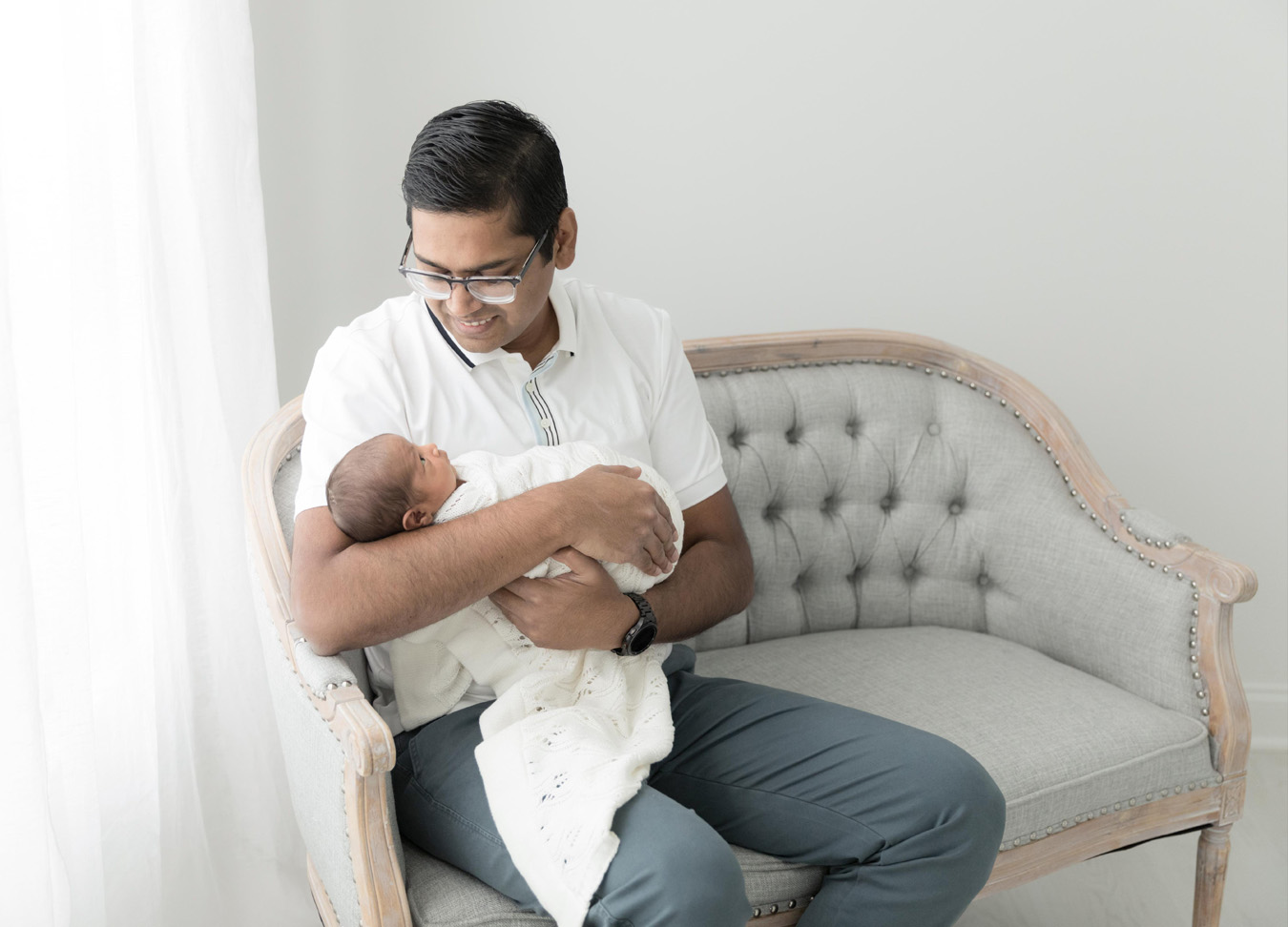 man holding his baby sitting on a chair and smiling