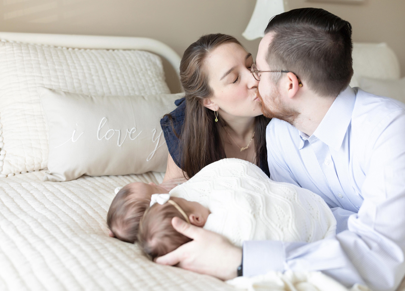 twin newborn session with parents kissing each other