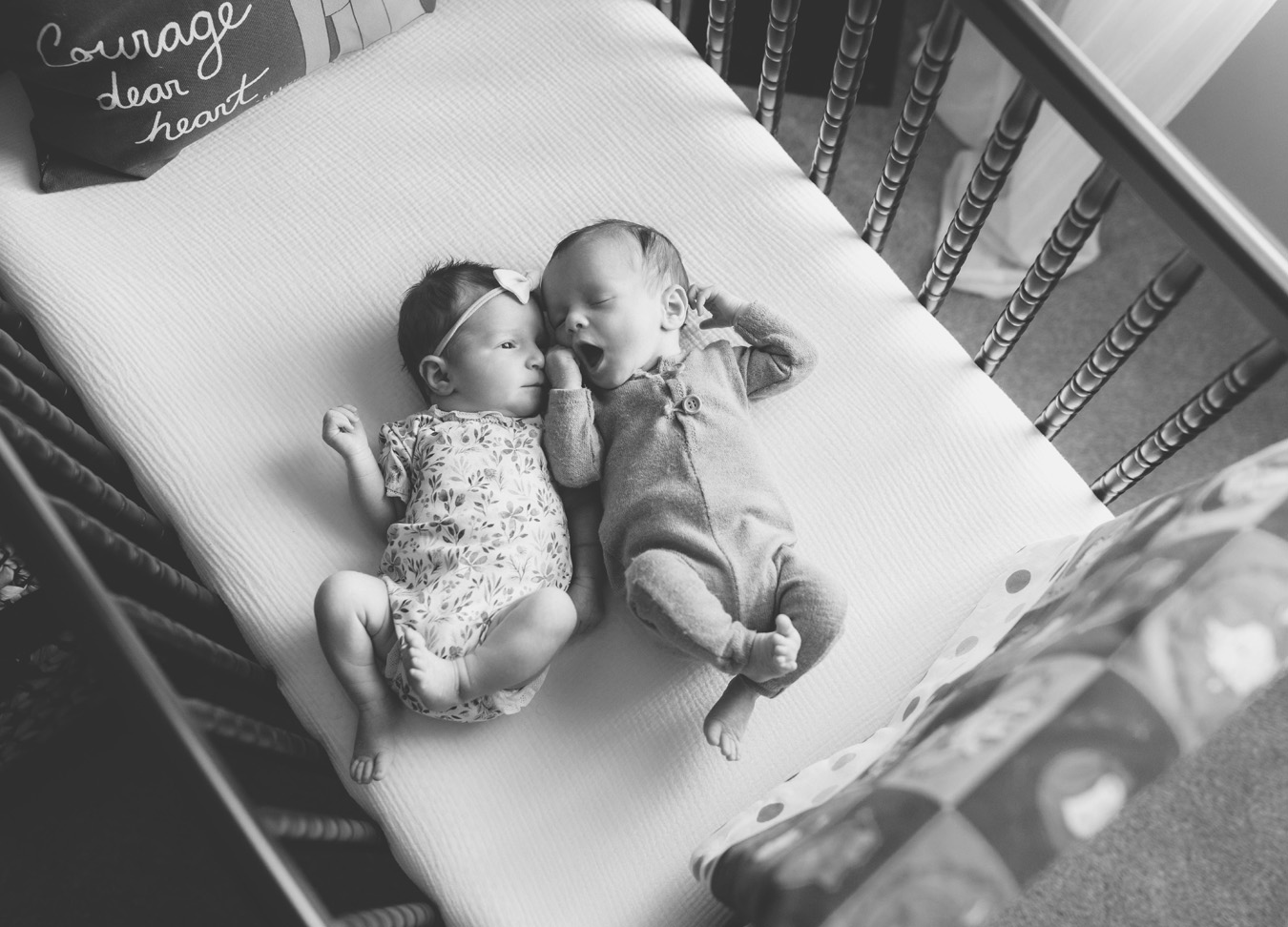 black and white picture of twins laying next to each other in the crib during a twin newborn session