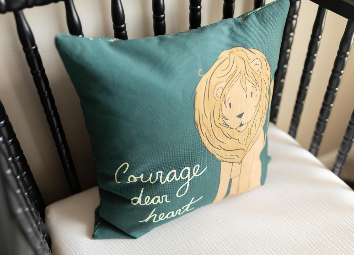 a green pillow in a black crib with the words "Courage Dear Heart"