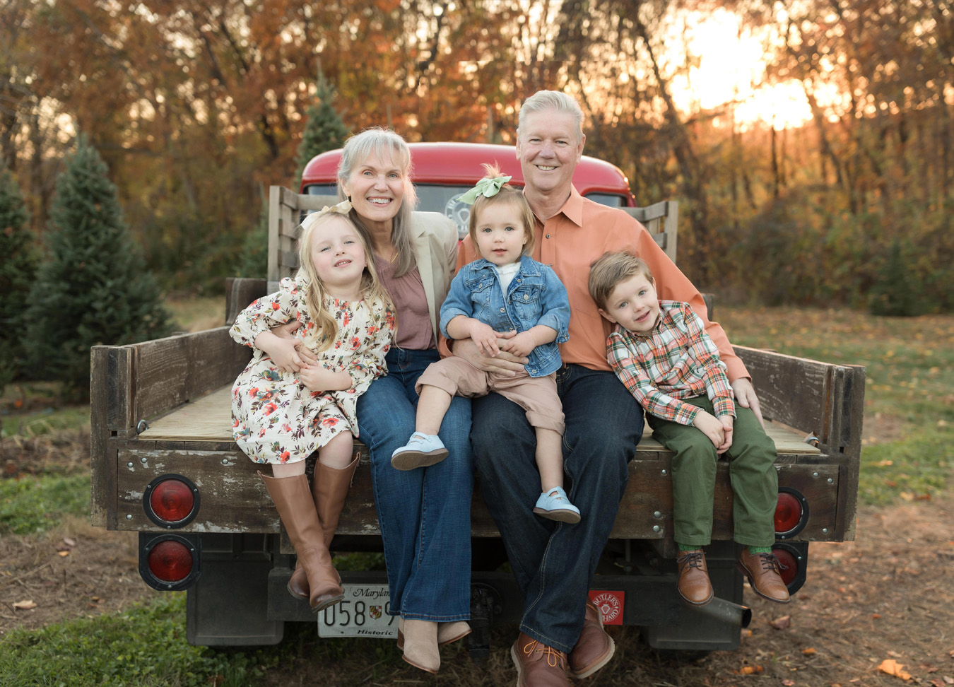 grandparents and grandchildren sitting on the bed of a truck