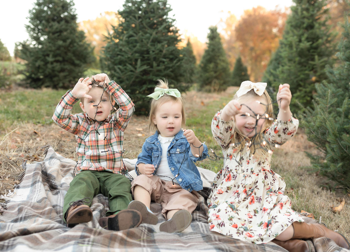 northern virginia family photographer captures three kids sitting on a blanket and playing with lights