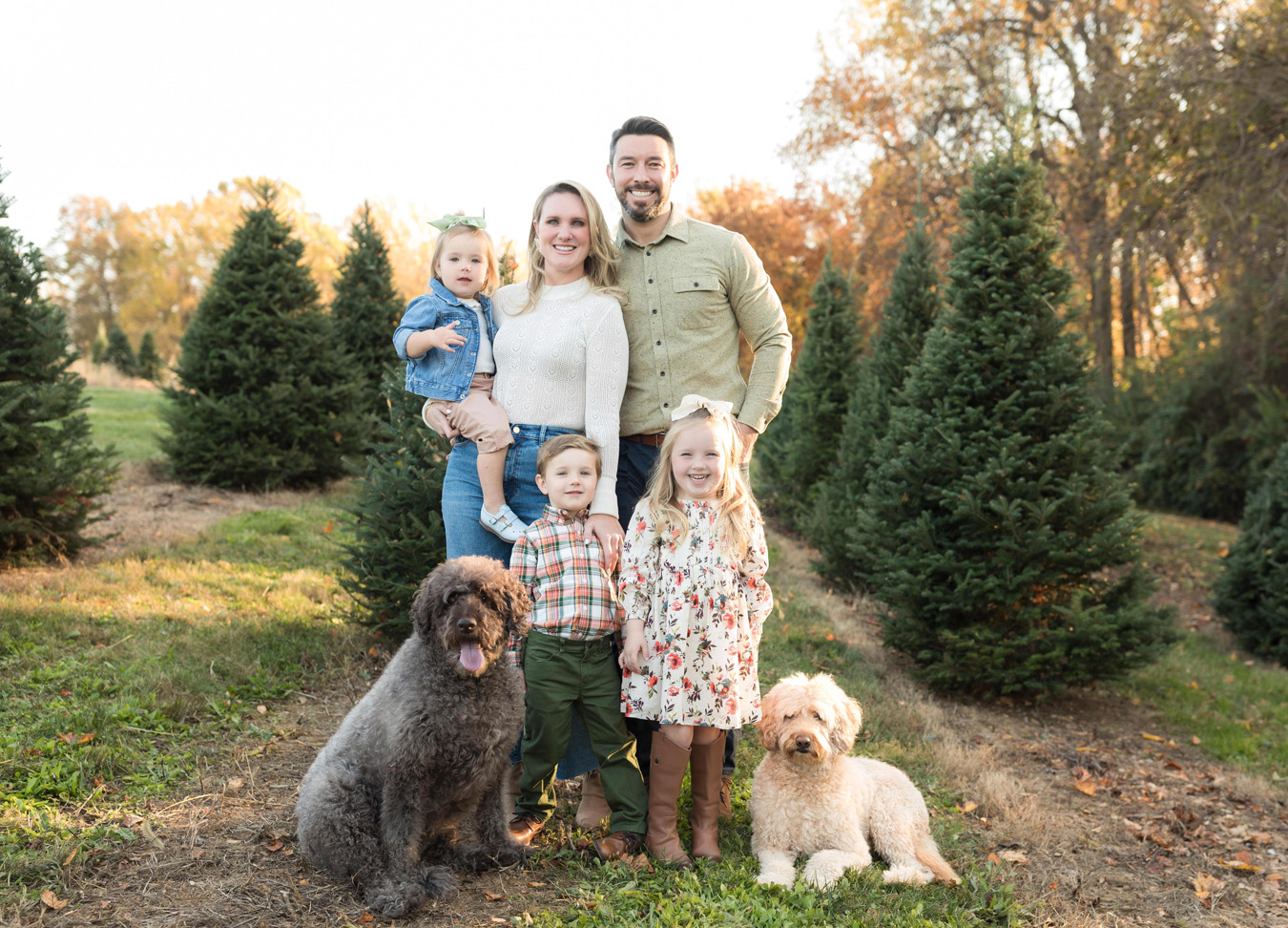 a family session captured by a northern virginia family photographer including a mom, dad, three kids, and two puppies standing in a tree field