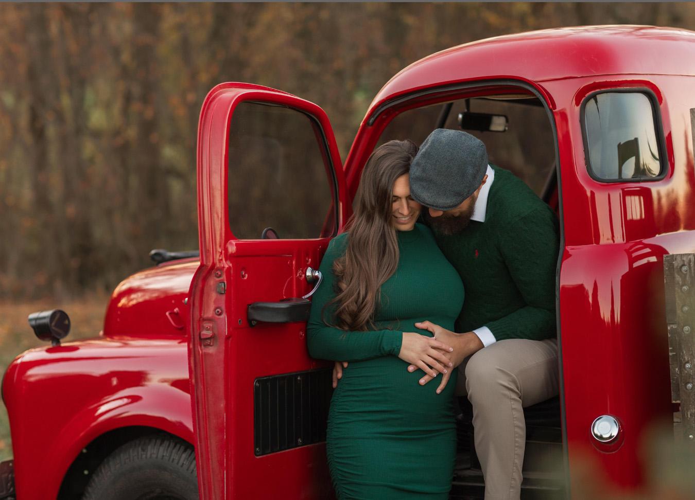Mom and dad sitting in the front seat of a red truck captured by a northern virginia maternity photographer