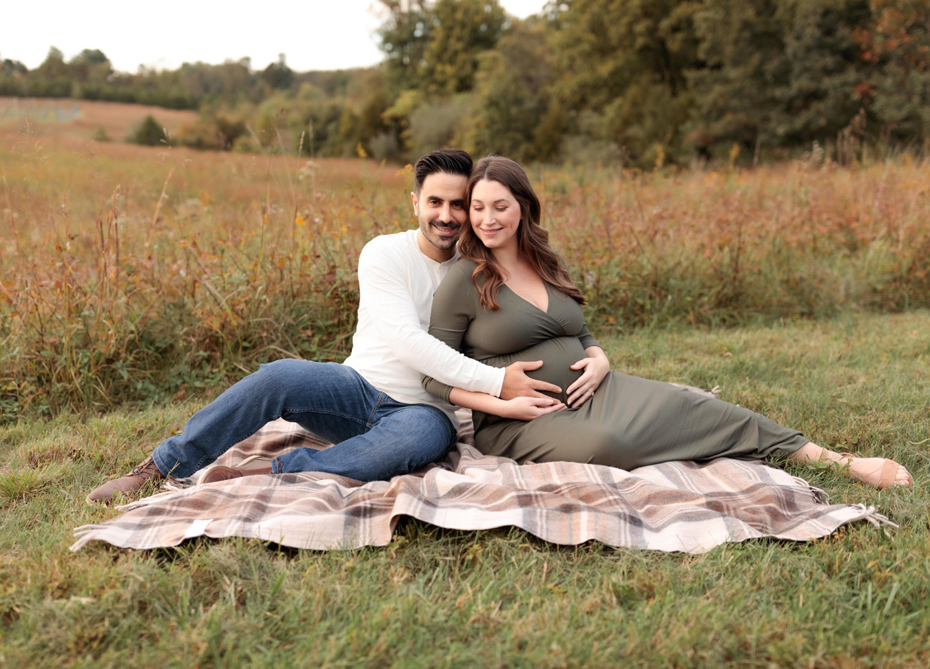 holiday foods to avoid during pregnancy featuring a mom and dad sitting on a blanket in a field