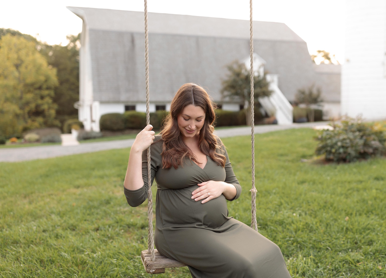 maternity session featuring a mom sitting on a swing