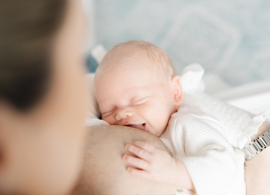 baby smiling while breastfeeding captured by a newborn photographer in Northern Virginia