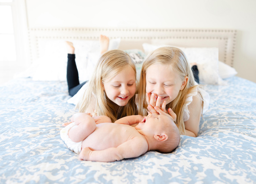 two girls smiling at their newborn sibling