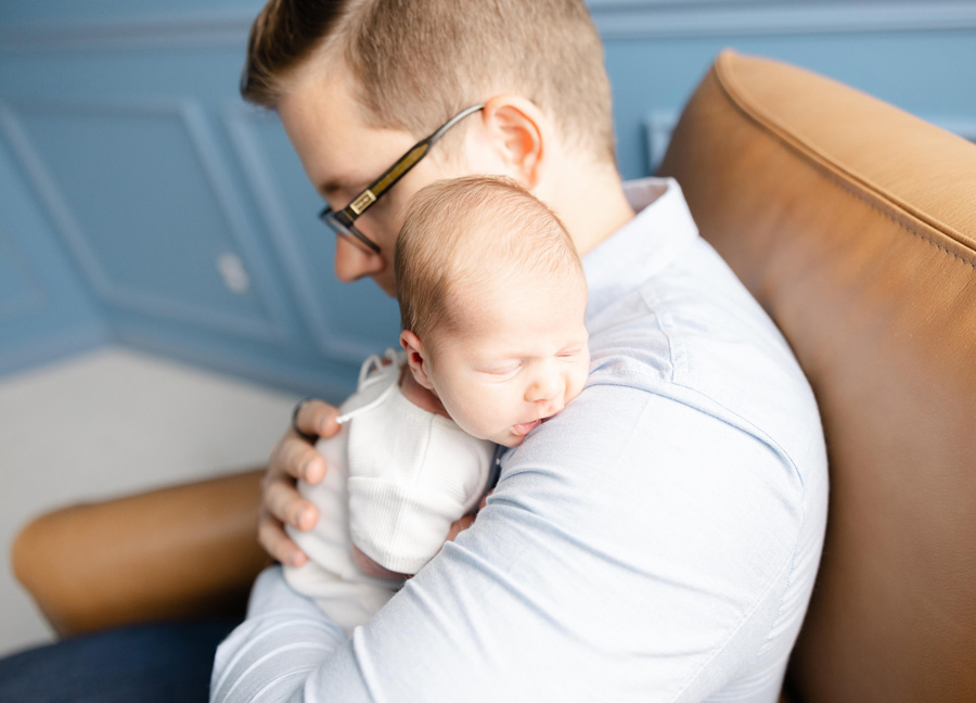 father and newborn snuggling caught by a newborn photographer in DC, Maryland, and Virginia