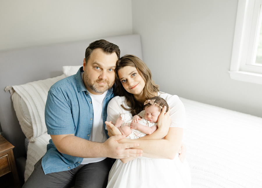 family portrait with a dad, mom, and babygirl in their bedroom captured by a washington dc newborn photographer