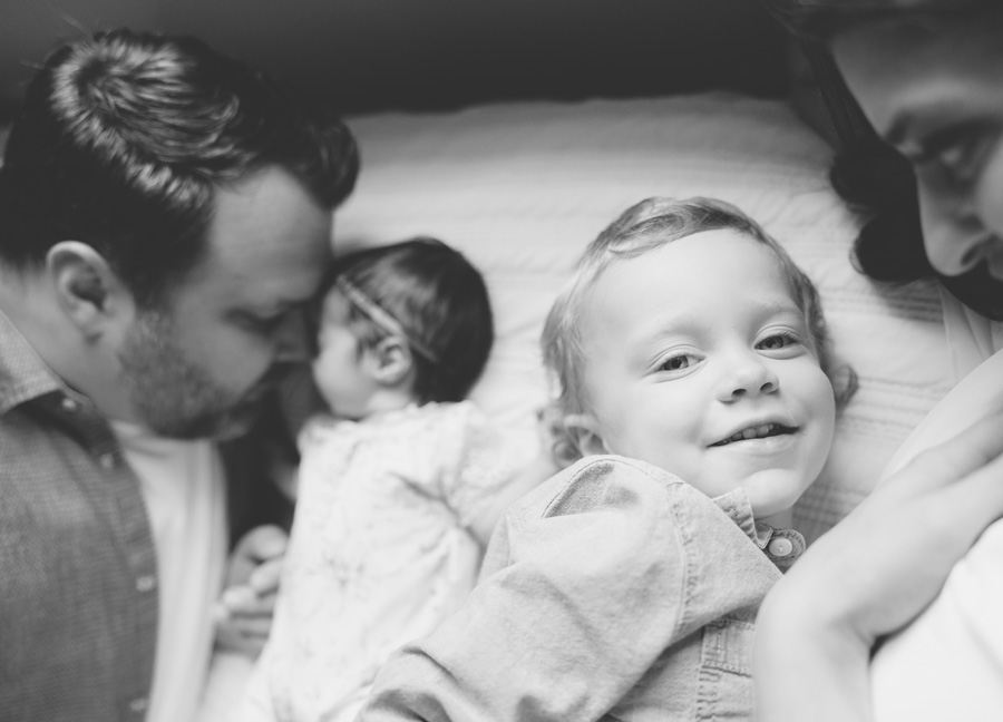 family photos snuggling on the bed featuring a mom, dad, sister, and brother